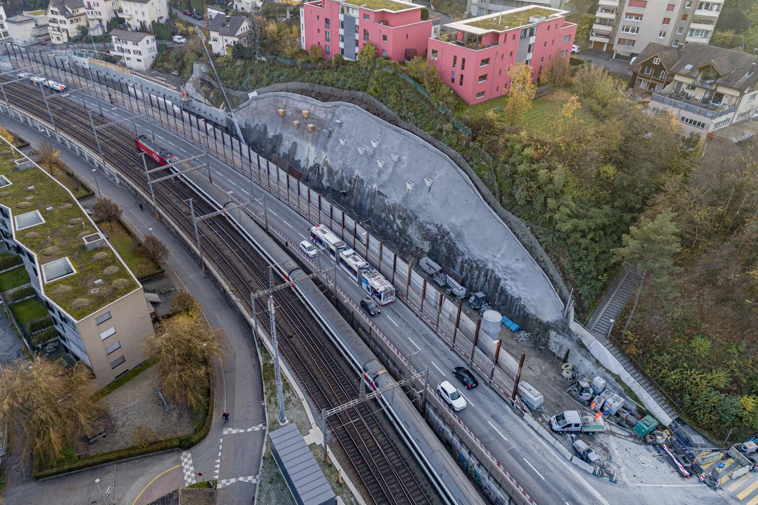 Bau der Stützmauer Stollbergrain hinter dem Schutzgerüst entlang der K13. Rückverankerte Betonwand (links oben im Bild) und Spritzbetonsicherung (Bildmitte; Aufnahme vom 19.11.21).