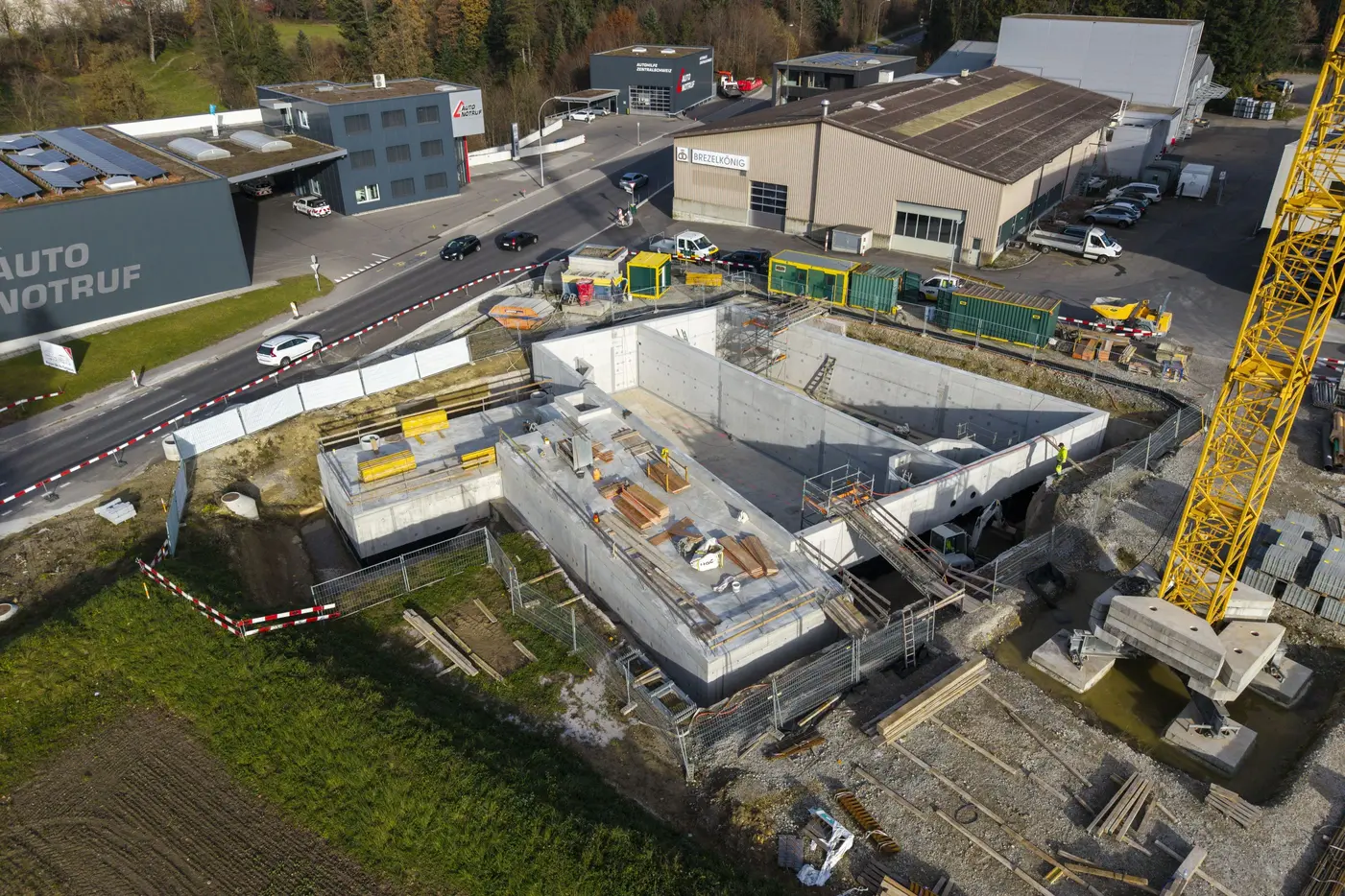 Baustelle mit Rohbau, Kräne und Baufahrzeuge in industrieller Umgebung.