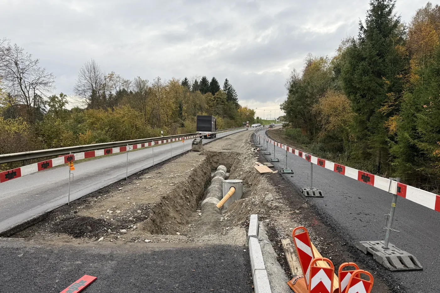Straßensperrung mit Baustelle, unbefestigte Fläche und orange-weißen Absperrungen.