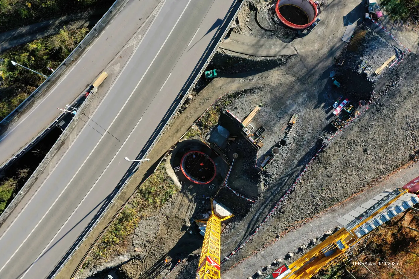 Blick auf Baustelle mit zwei kreisförmigen Gruben neben einer Straße.