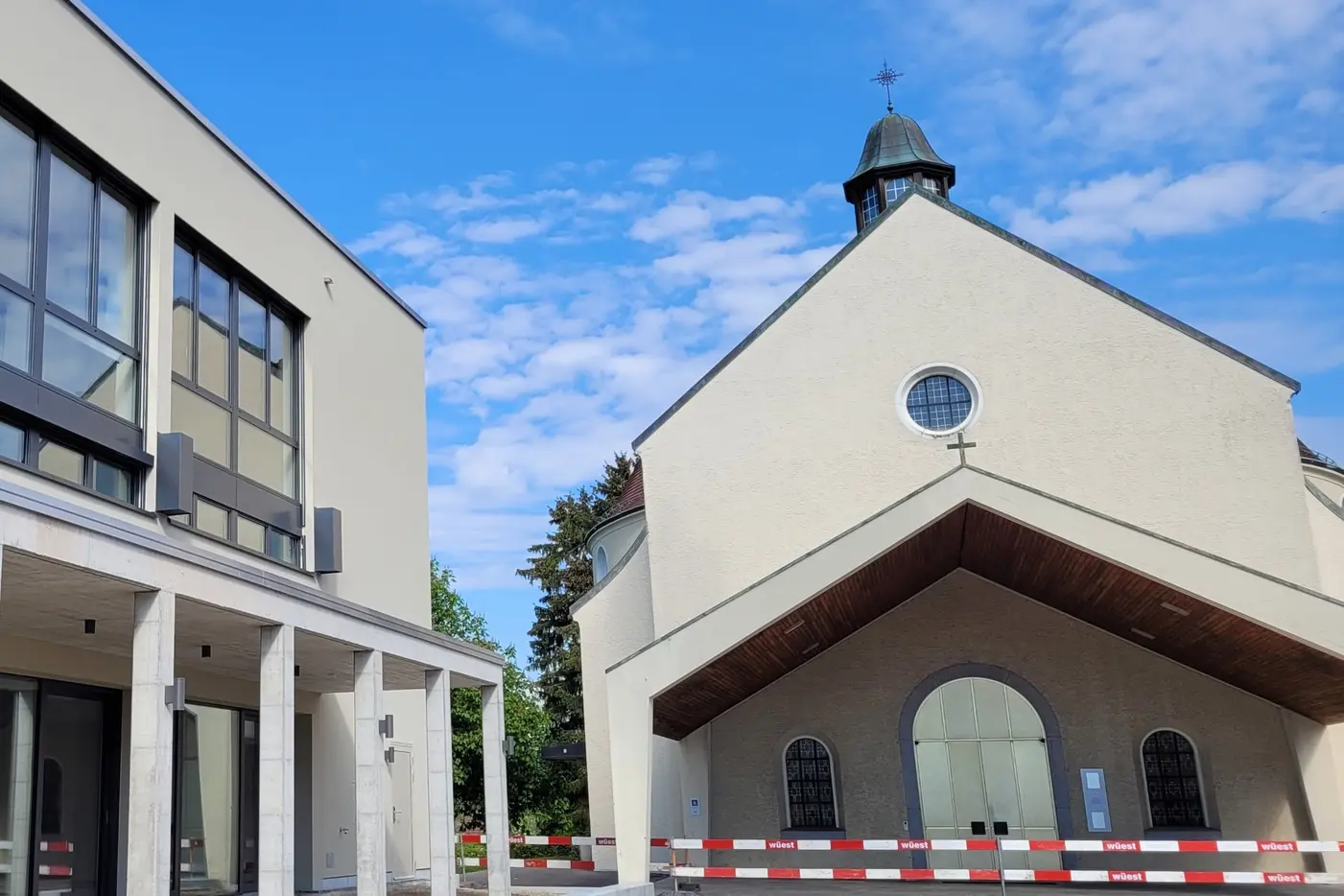 Moderne Gebäude neben einer Kirche mit einem blauen Himmel im Hintergrund.