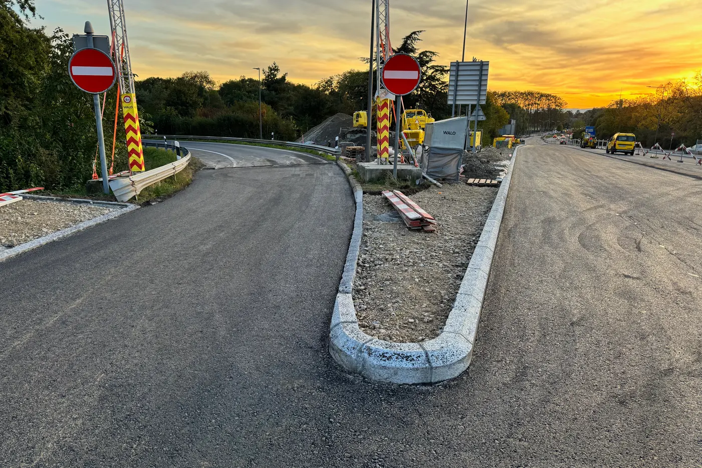 Nouvelle route avec panneaux de circulation et coucher de soleil en arrière-plan.