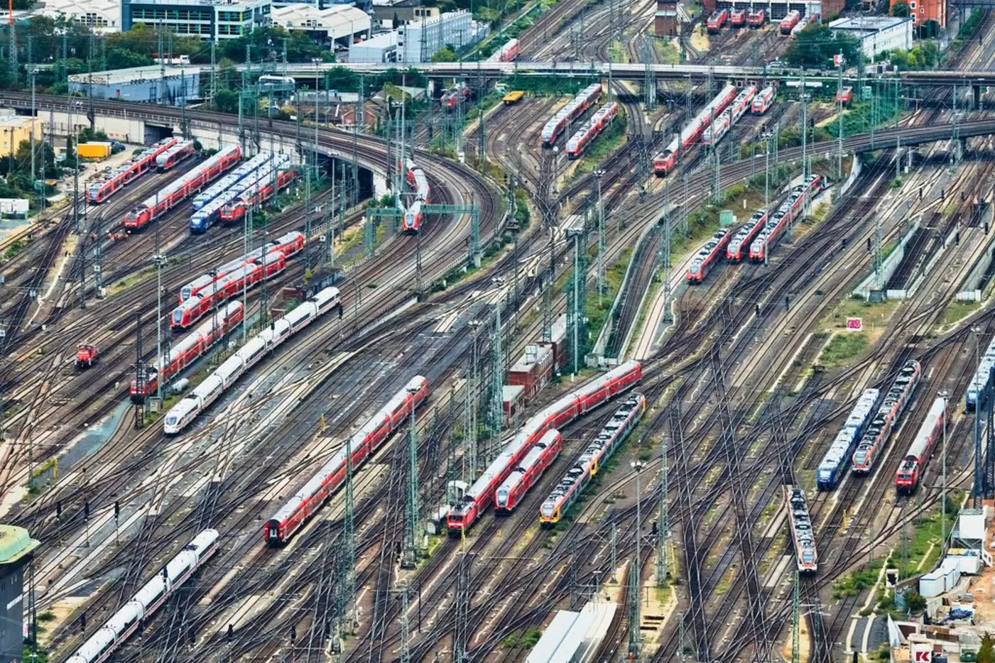 Aerial view of a busy railway yard with multiple red and silver trains on winding tracks.