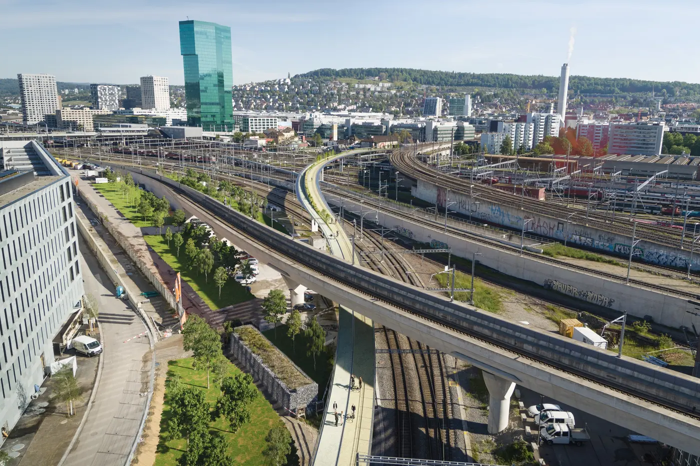 Stadtansicht mit Verkehrswegen, Bahngleisen und modernen Gebäuden im Hintergrund.
