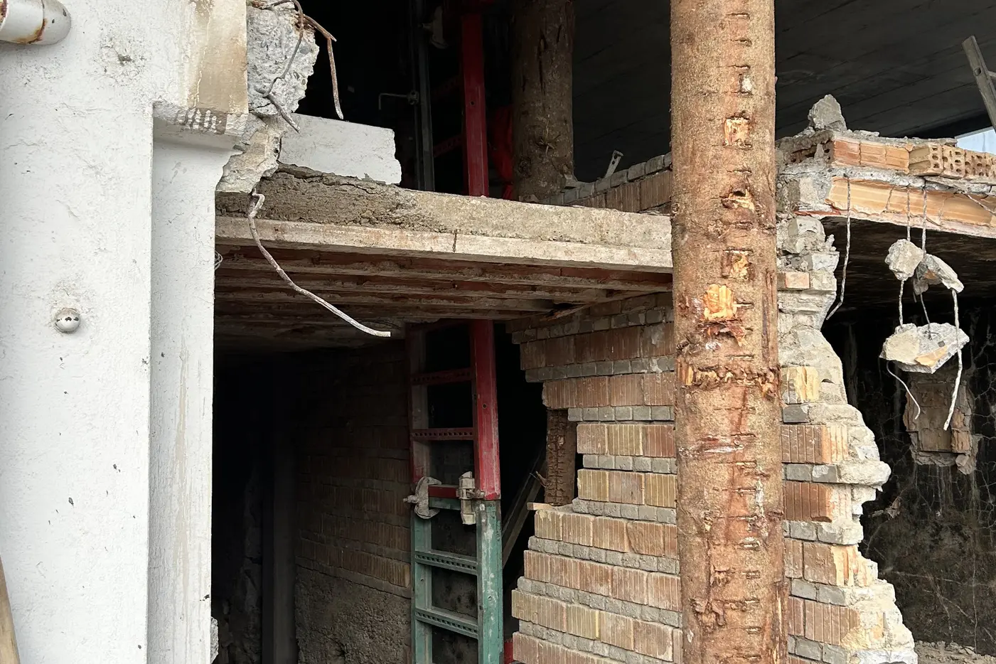 Blick auf eine Baustelle mit beschädigten Wänden und einer grünen Leiter.