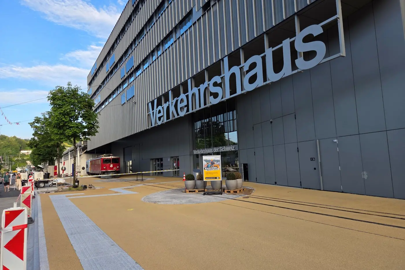 Modernes Gebäude des Verkehrshauses mit großem Schriftzug und gepflastertem Weg.