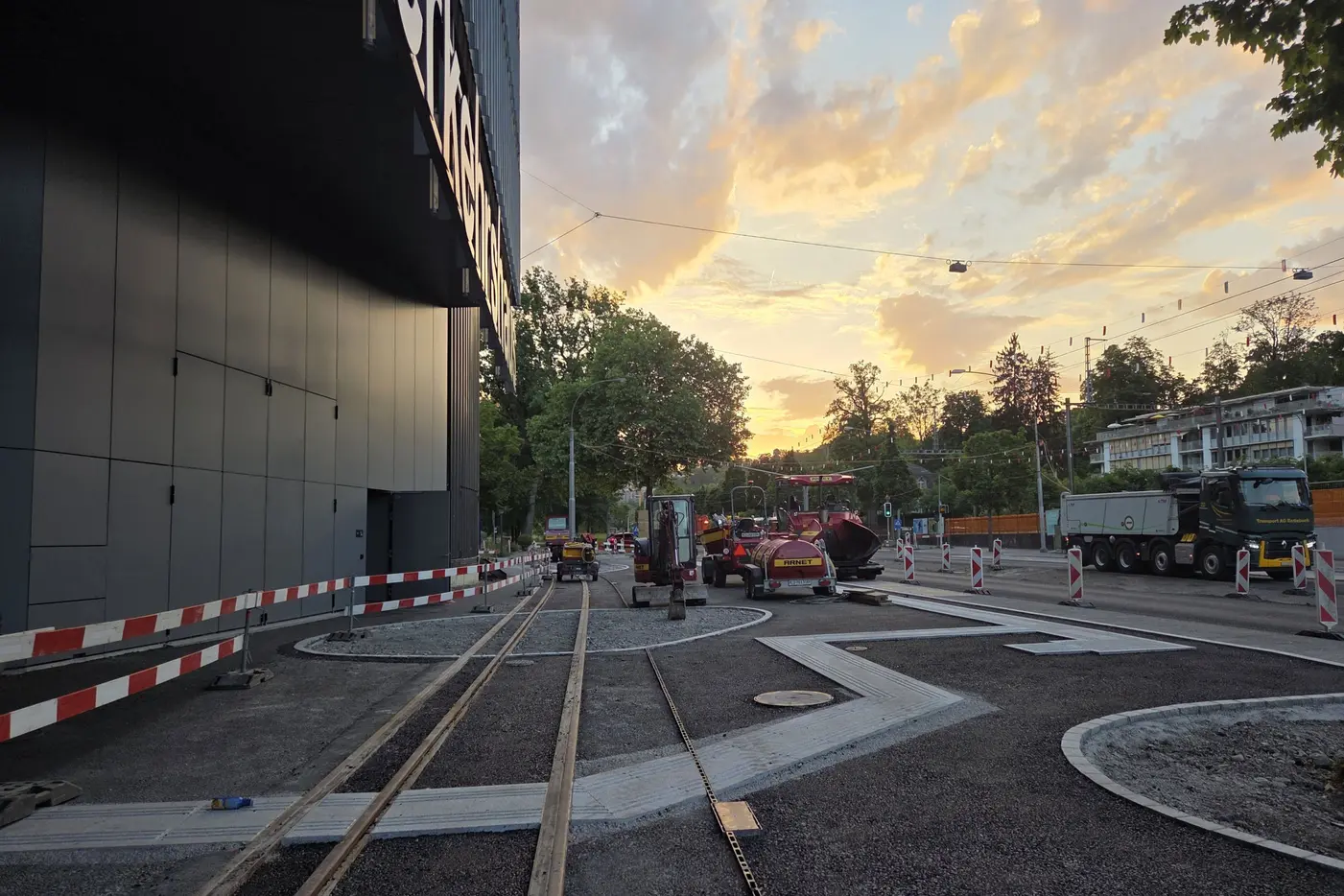 Bauarbeiten an der Straßenbahn mit einem bunten Sonnenuntergang im Hintergrund.