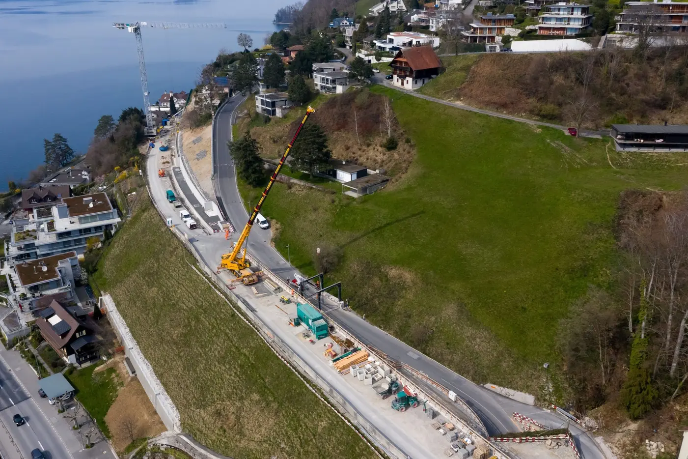 Baustelle mit Kranausrüstung, Straßenarbeiten und Aussicht auf den See in ländlicher Umgebung.
