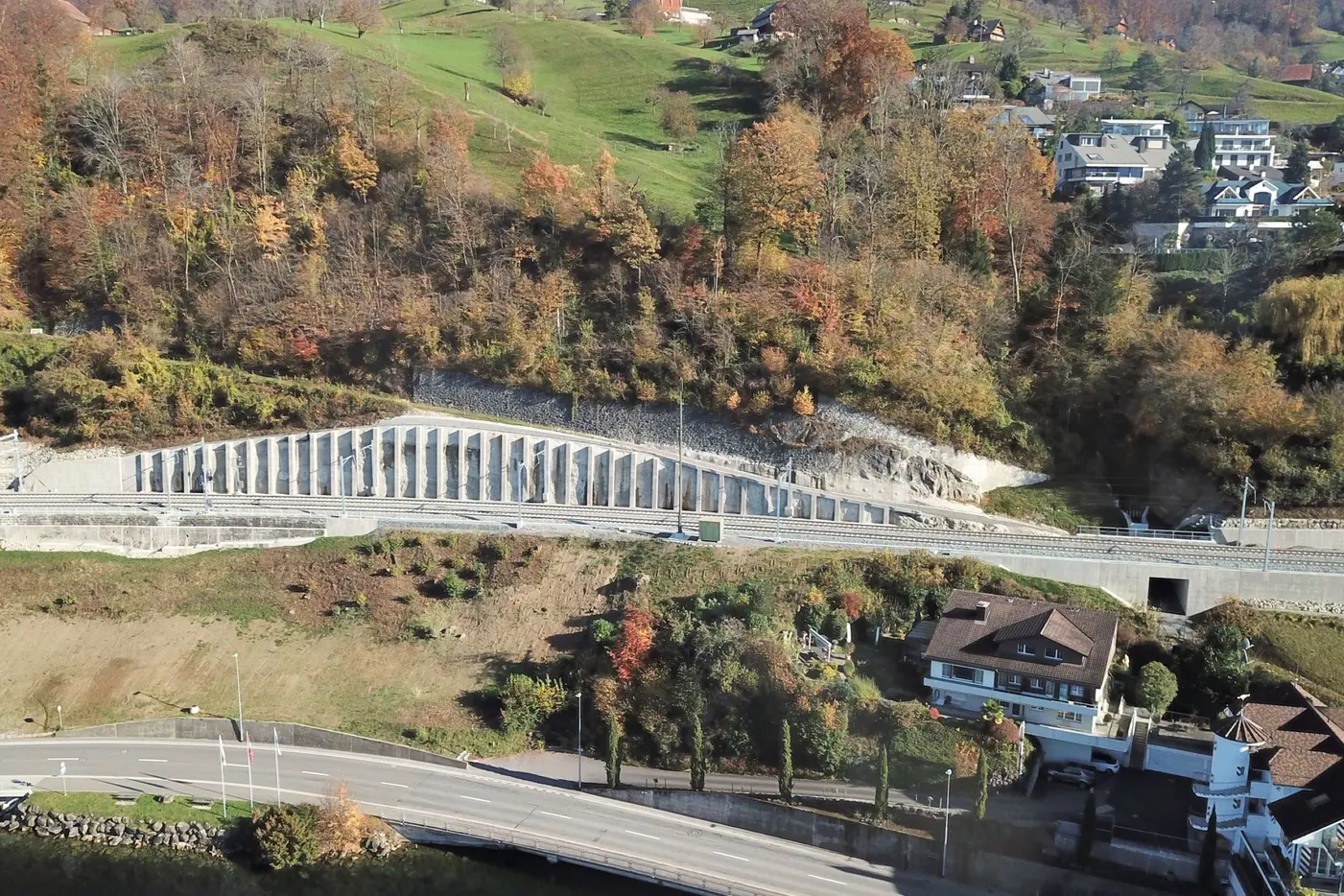 Luftaufnahme einer Landschaft mit einer Straßen- und Uferlinie, eingebetteten Säulen und buntem Laub.