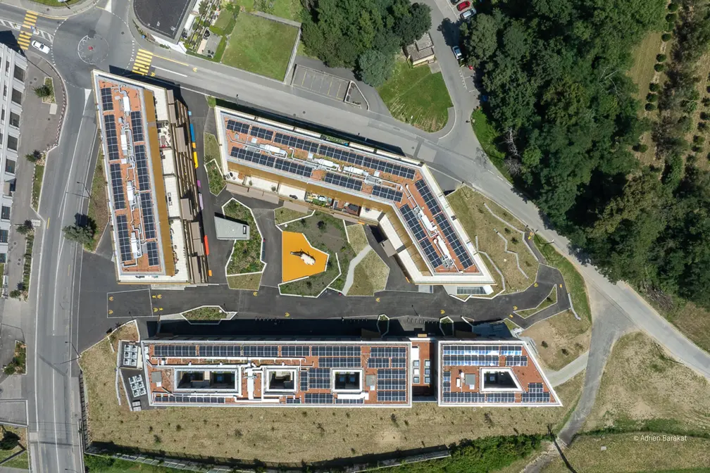 Luftaufnahme eines modernen Wohnkomplexes mit grünen Flächen und parkähnlichen Bereichen.
