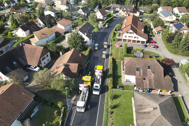 Blick auf eine Wohnstraße mit Baustellenfahrzeugen und Häusern in der Umgebung.
